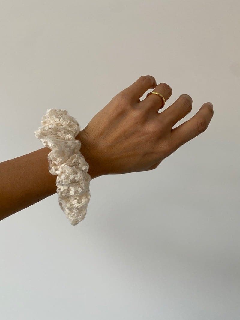 Hand mit schönem Haar Scruncie am Handgelenk in der Farbe weiss mit Blumenmuster